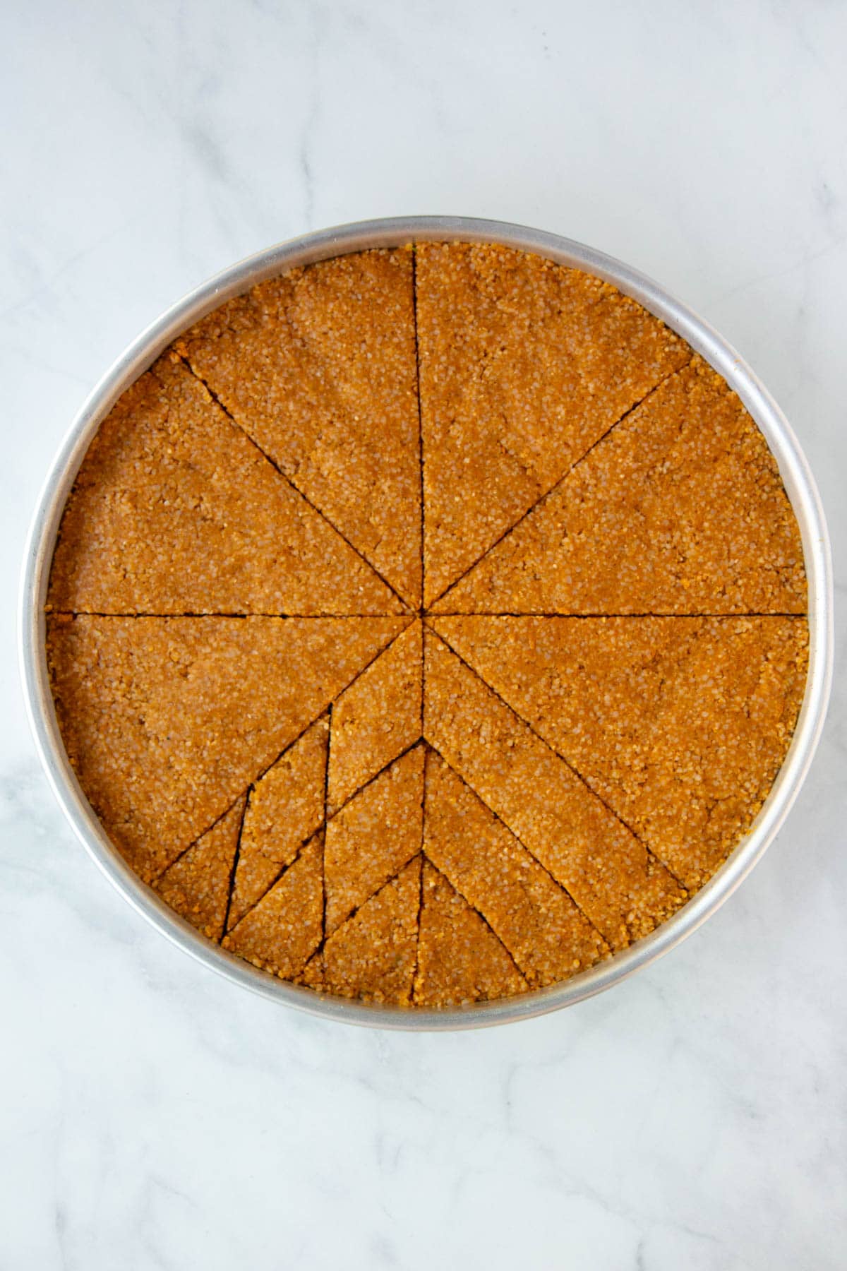 Unbaked kibbeh with 1 wedge cut into 3 equal portions, and an adjacent wedge cut into diamonds.