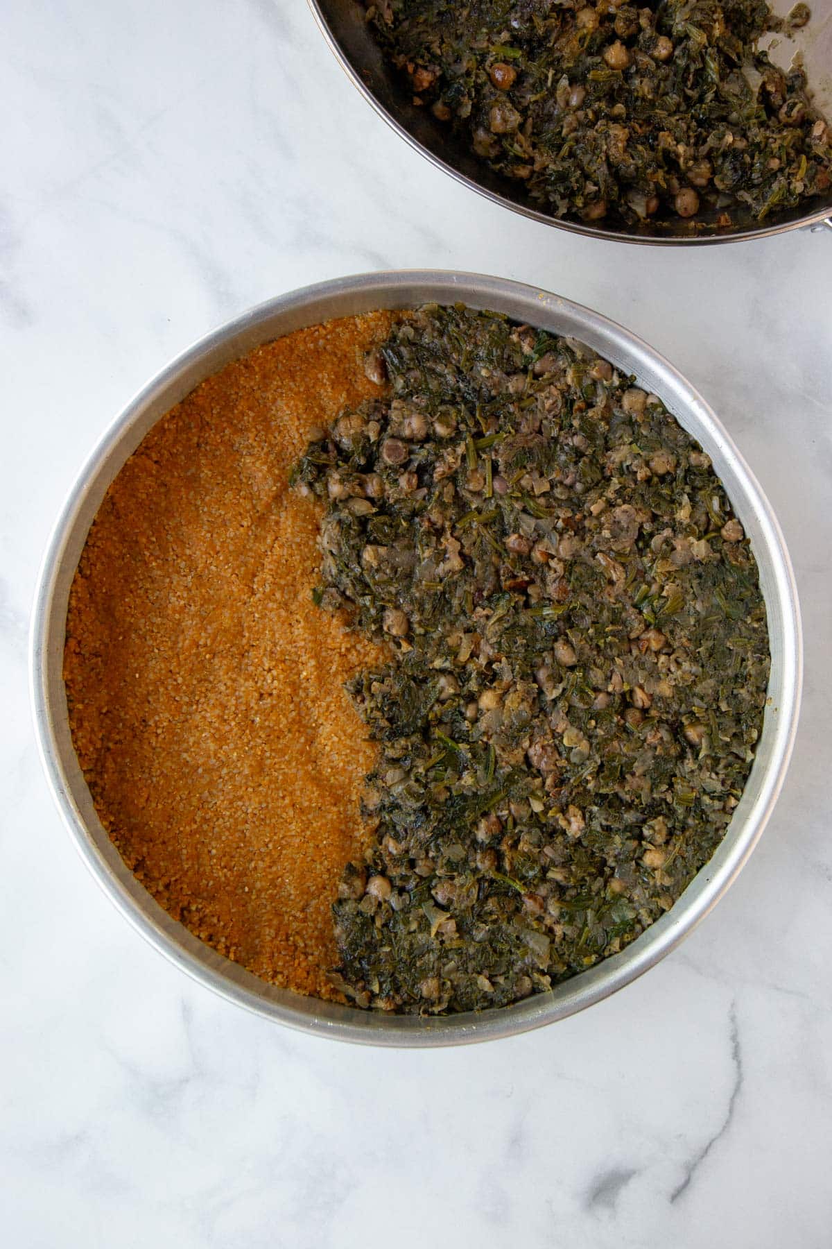 Topping the bottom layer of pumpkin kibbeh dough with the spinach and chickpea filling.