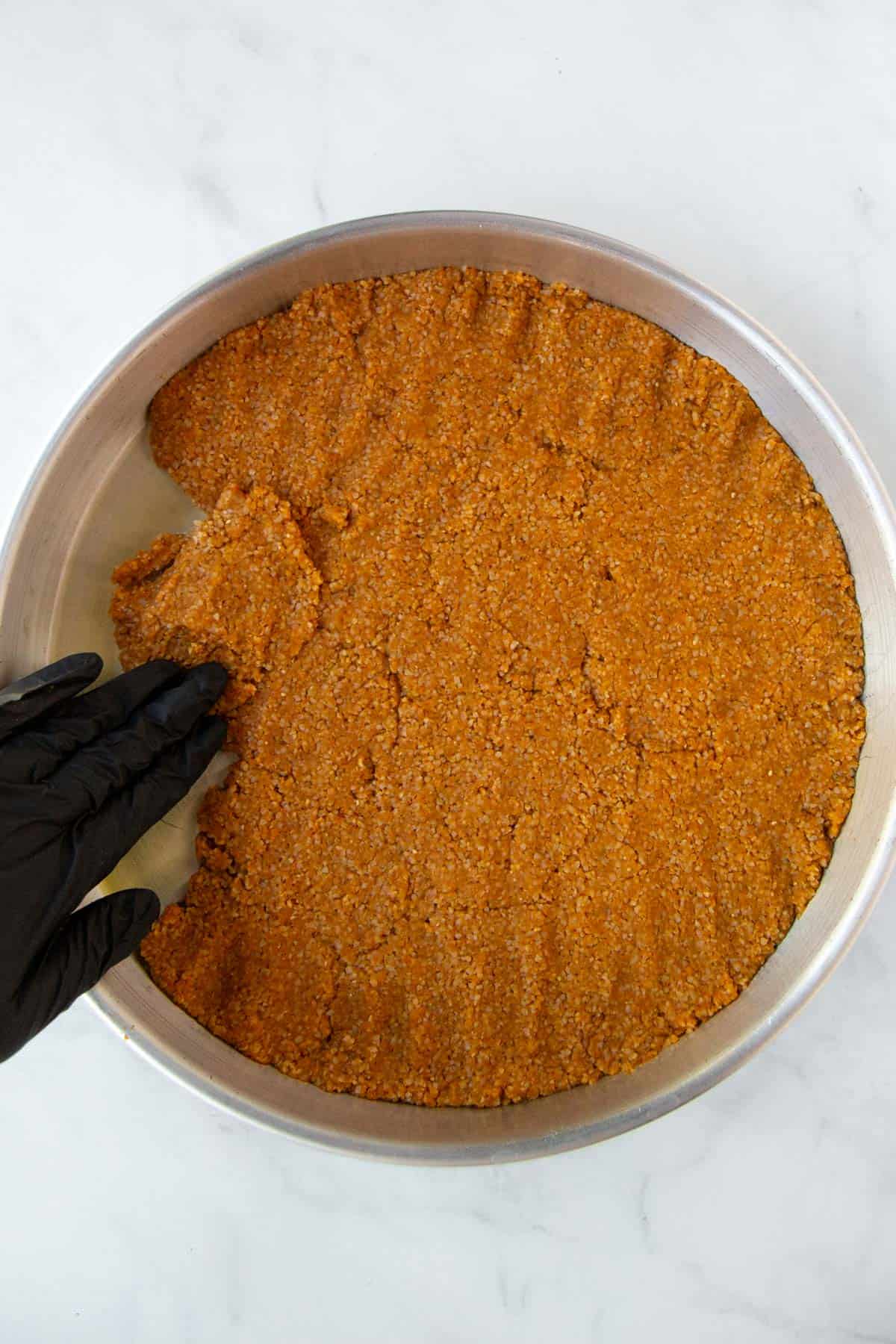 Pressing down the first layer of pumpkin kibbeh dough into the tray.