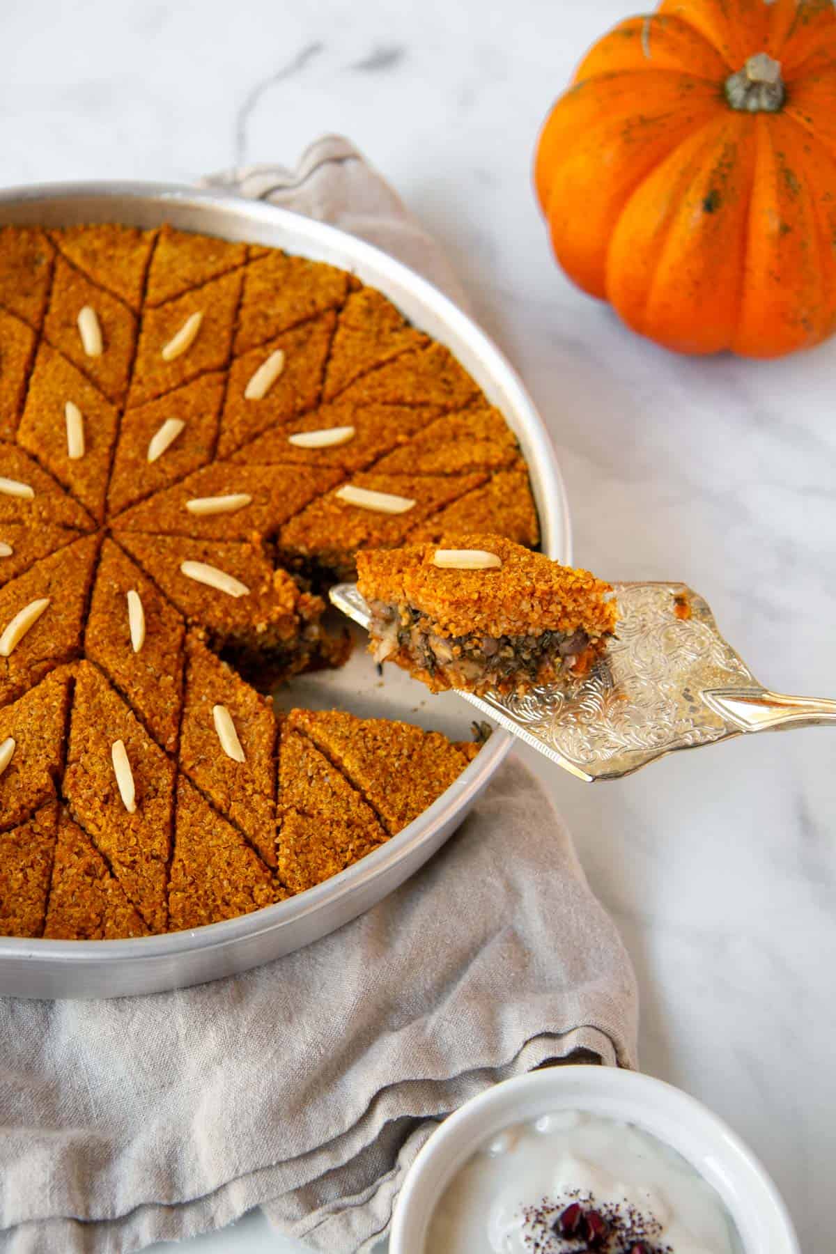 Lifting a slice of pumpkin kibbeh out of the tray.