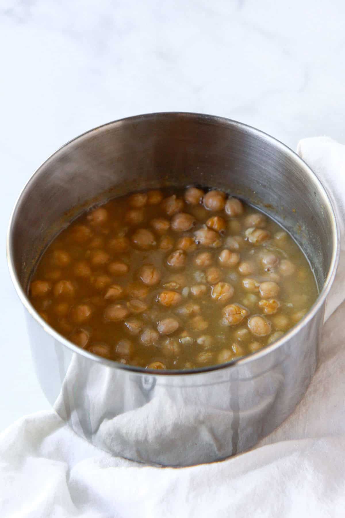 Balila chickpeas being simmered with cumin, garlic, and salt in the pot.