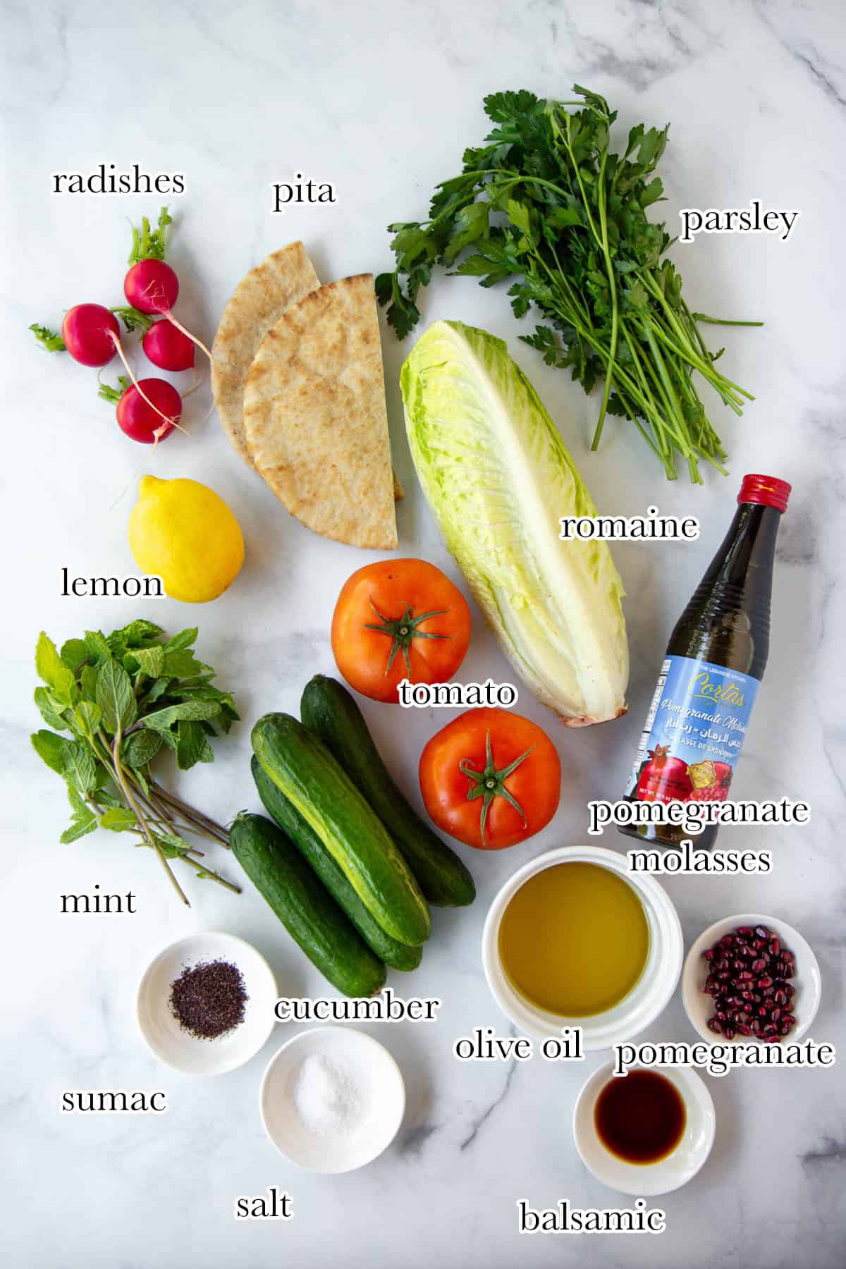 Ingredients needed for fattoush salad laid out on a marble surface.